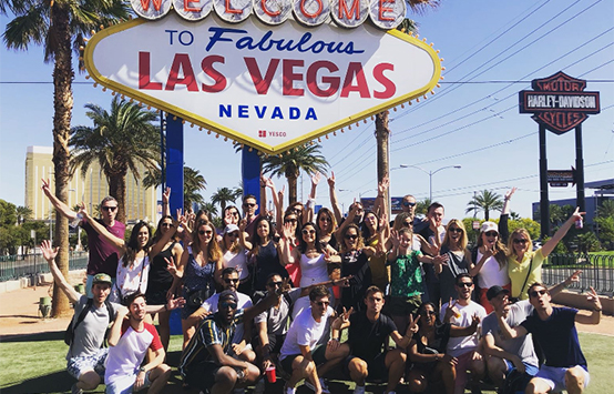 Un groupe de personnes posant devant l'emblématique panneau 'Welcome to Fabulous Las Vegas, Nevada' par une journée ensoleillée.